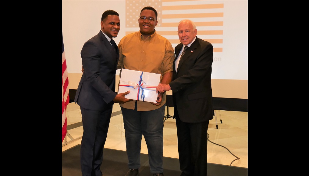 US Embassy Black History Month Photo Competition winner Jason Tomlinson (centre) receives his prize from US Ambassador Donald Tapia (right) and Jeremiah Knight, Counsellor for Public Affairs in the US Embassy.